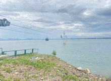 a cable car going over a body of water with mountains in the background