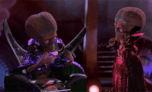 a couple of aliens are standing next to each other in a dark room