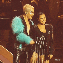 a man in a blue fur coat and a woman in a black dress are standing next to each other