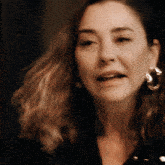 a woman wearing a pair of hoop earrings looks at the camera
