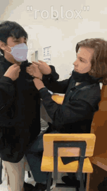 a boy wearing a mask is standing next to another boy wearing a mask in a room .