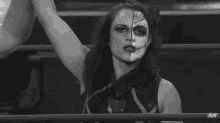 a black and white photo of a wrestler with half of her face painted .