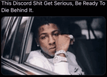 a man is sitting in a car with his hand on his face and a caption that says this discord shit get serious