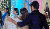 a man and a woman are hugging each other in a room with people .