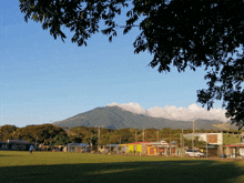 a soccer field with a mountain in the background and houses in the foreground