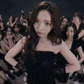 a girl in a black dress stands in front of a group of girls