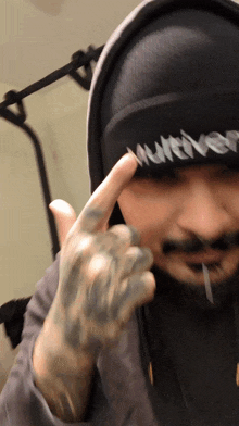 a man wearing a hat that says " whatever " is giving the middle finger