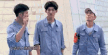 a group of men in blue overalls are standing next to each other .