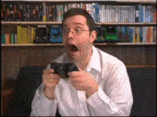 a man with glasses is playing a video game with his mouth open