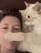 a cat petting a woman 's face with its paws