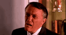 a man in a suit and tie is making a funny face in a room .
