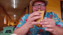 a man wearing glasses and a hat is eating a piece of food