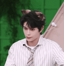 a man in a striped shirt and tie is wearing a cat ear .