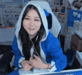 a woman wearing a blue jacket with a white hood is sitting at a desk