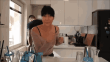 a woman is standing in a kitchen holding a glass of milk