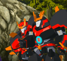 two transformers are standing next to each other in front of a rock wall