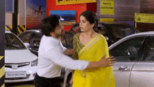 a woman in a yellow saree is being hugged by a man in a white shirt