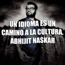 a man with glasses stands in front of a brick wall with the words un idioma es un camino a la cultura