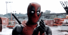 a man in a deadpool costume is holding a gun .