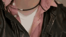 a person wearing a pink shirt and a black leather jacket .