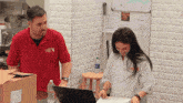 a man in a red shirt with a x on it is standing next to a woman