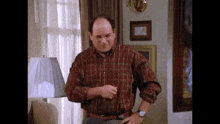 a man wearing glasses and a plaid shirt is standing in a living room .