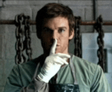 a man wearing a white glove is holding his finger to his mouth .