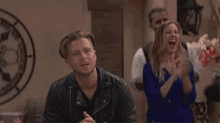 a man in a leather jacket is clapping his hands in front of a group of people at a party .