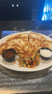 a plate of quesadillas with salsa and sour cream on a table