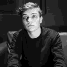 a young man is sitting on a couch in a black and white photo .