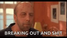 a bald man with a beard is sitting in a living room with his eyes closed and a black eye .