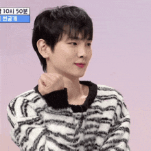 a young man wearing a zebra print sweater has his fist up in the air
