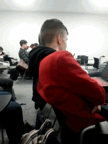 a man in a red sweatshirt sits in a classroom
