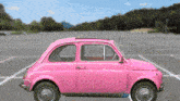 a pink car is parked in a parking lot with mountains in the background