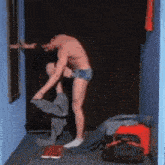 a shirtless man is putting on a pair of shorts in a dressing room .