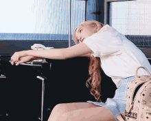 a woman wearing a white shirt and a blue skirt is leaning on a table