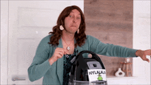 a woman in a wig is holding a vacuum cleaner with a label that says hylala