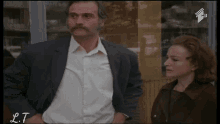a man in a suit is talking to a woman in a blurry photo with lt written on the bottom