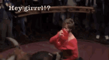 a man in a red shirt is riding a bull and says hey girrrl ?