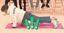 a man is doing push ups on a yoga mat while other people sit on stools .