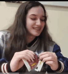 a girl is smiling while holding a packet that says coca cola