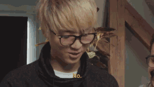 a man wearing glasses is talking to another man while holding a card .