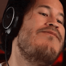 a man with a beard wearing headphones and making a face