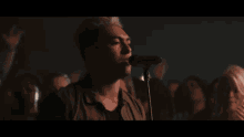a man singing into a microphone in front of a crowd of people