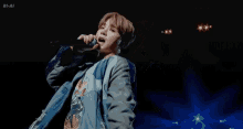 a man is singing into a microphone on stage .