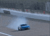 a blue race car is driving down a race track and smoke is coming out of it .