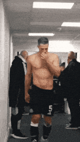 a shirtless soccer player with the number 45 on his shorts walks down a hallway
