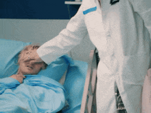 a man in a white coat with a black badge on his chest is standing next to a patient in a hospital bed