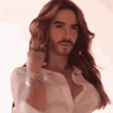 a man with long hair and a beard is holding his hair