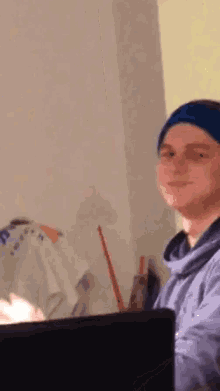 a man wearing a blue headband is smiling while sitting in front of a computer